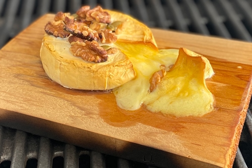 cheese-cedar-plank Camembert with walnut topping on a grilling plank