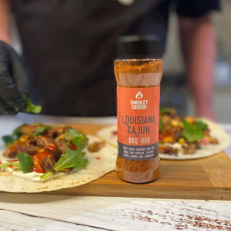 Cajun-scaled-e1673881586774-jpg Louisiana Cajun BBQ rub with smoked paprika on wooden table with tacos in the background.