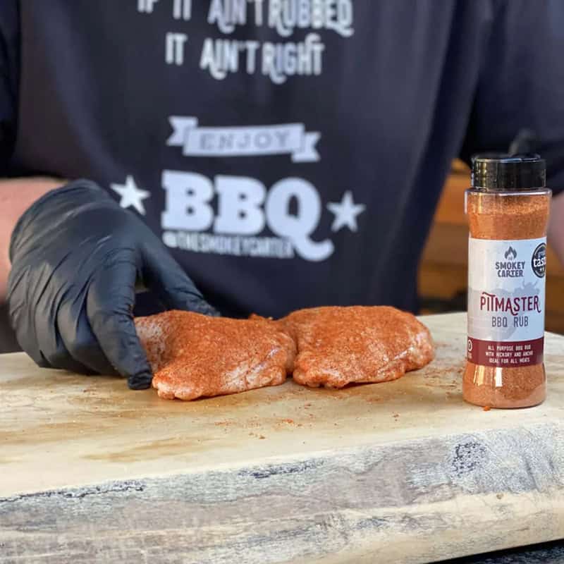 Juicy raw steak seasoned with Pitmaster BBQ Rub on a wooden cutting board, ready for grilling, showcasing high-quality meat and barbecue spices from Smokey Carter.