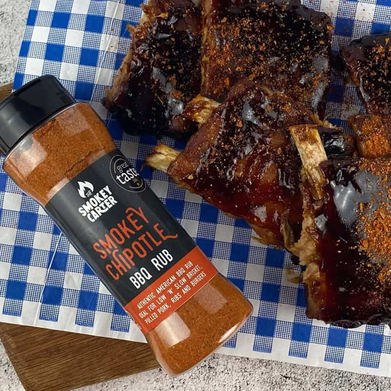 Smoke chef BBQ rub and glazed pork ribs on blue checkered paper, ideal for grilling or smoking, flavored with Cedar Works premium wood products for optimal barbecue flavor.