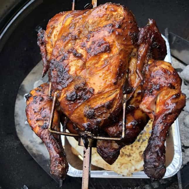 Slow-cooked roasted whole chicken with golden crispy skin, seasoned to perfection on a cedar wood grill, ideal for BBQ lovers and outdoor cooking enthusiasts.