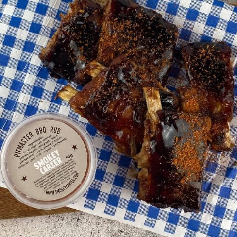Smoked beef ribs with BBQ rub sauce served on a checkered cloth at Cedar Works, showcasing premium smoked meats.