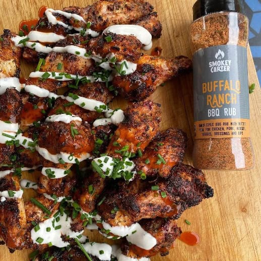 image033 Juicy grilled chicken wings topped with creamy sauce and fresh herbs, served alongside smoky BBQ sauce in a clear bottle for a flavorful meal. Perfect for outdoor cooking or barbecues.