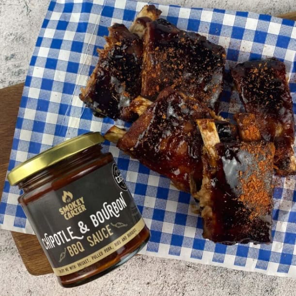 Savory glazed pork ribs topped with barbecue sauce and spices, served with smoky chipotle and bourbon BBQ sauce. Perfect for outdoor grilling and backyard barbecues.