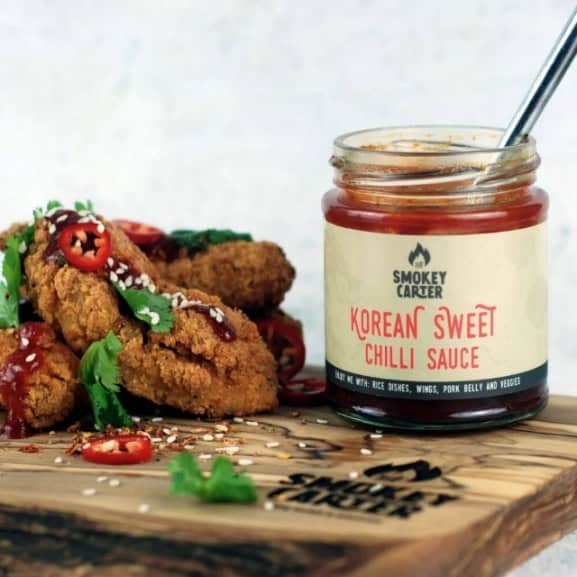 image047 Korean sweet chili sauce in a glass jar with fried chicken and chili peppers on a wooden serving board, highlighting vibrant flavors and spicy dipping sauce.