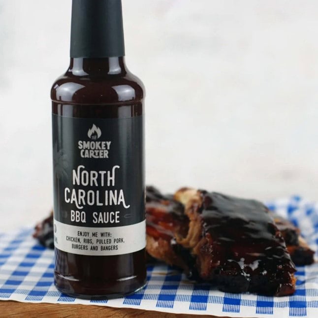Smokey Carter North Carolina BBQ sauce bottle with ribs on blue checkered cloth, ideal for adding rich, smoky flavor to grilled meats and barbecue dishes.