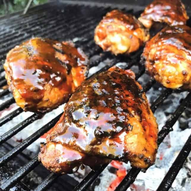 Juicy grilled chicken thighs with savory barbecue glaze cooking on outdoor barbecue grill. Perfect for summer cookouts and outdoor gatherings.